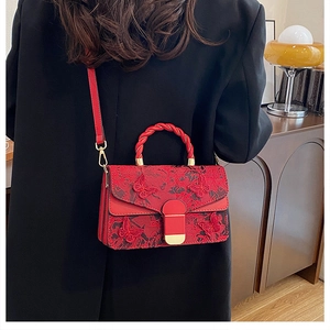 Détail du sac rouge avec broderie papillon en dentelle et poignée tissée pour femmes