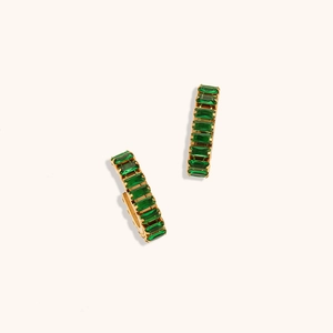 Détail de boucles d'oreilles dorées en O avec zircons rectangulaires vert émeraude