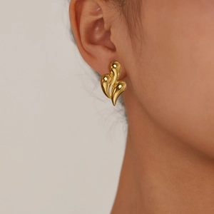 Detail of gold teardrop earrings worn by a model showing the elegant geometric design