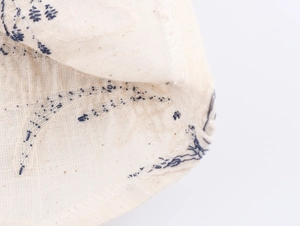 Close-up of high-quality navy blue embroidery on premium beige faux linen fabric