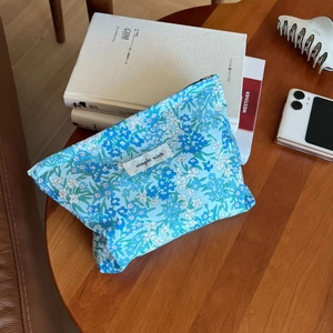 Close-up of a floral canvas makeup pouch with a blue liberty print and simple wish label