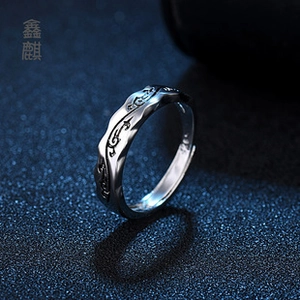 Close-up of silver feather ring showing vintage black carved textures and adjustable open band