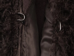 Detailed macro view of hook-and-eye closure on dark brown faux fur jacket with silk lining