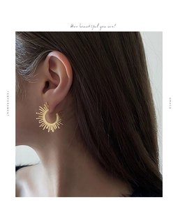 Detailed close-up of golden sunburst fan earrings featuring radiating metal spokes