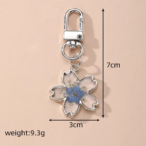 Detailed view of handmade cherry blossom resin keychain with real blue flowers and size specs