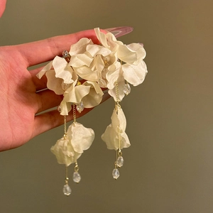 Close-up of elegant oversized white fabric flower tassel earrings for summer vacation