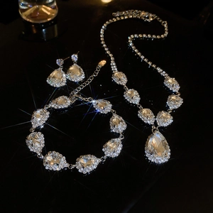 Elegant silver teardrop rhinestone necklace and earring set on reflective black surface