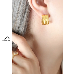 Close-up of gold chunky hoop earring and emerald cut crystal ring in stainless steel