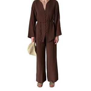Dettaglio del top a maniche lunghe con scollo a V e pantaloni larghi in tessuto plissettato