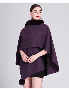 Detail of deep purple knitted poncho with faux rabbit fur collar and fluffy pompom charm