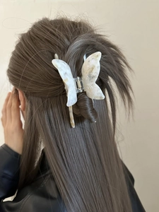 Detail showing a white butterfly hair claw clip with acetate marble texture on hair