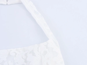 Close-up of elegant white lace embroidery and halter neckline details on a summer dress