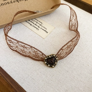 Detail of vintage brown lace choker featuring a dark brown heart pendant with pearl accents