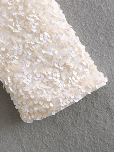 Macro shot of high-density white sequins and embroidery details on the winter short jacket