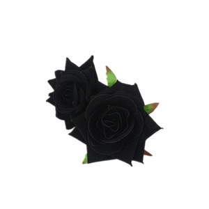 Detailed close-up of double black velvet faux roses with green leaves for hair accessories