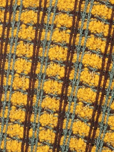 Macro shot of textured knit fabric with yellow, brown, and grey intertwined yarn detail
