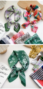 Close-up of lightweight square silk scarves with floral and paisley prints on wood