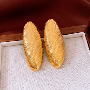 Grandes boucles d'oreilles ovales dorées avec rayures diagonales sur boîte à bijoux en bois