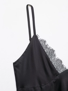 Détail d'un caraco noir en satin avec bordure en dentelle et fines bretelles