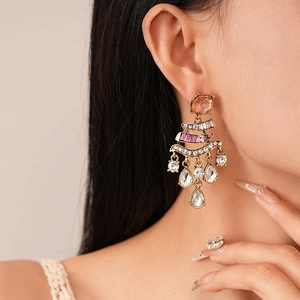 Close-up of pink gemstone drop earrings with golden tassels shown on a model