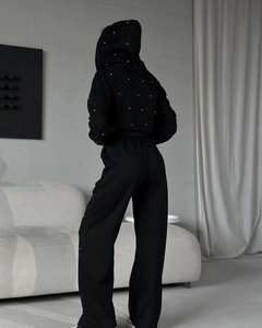 Detailansicht der Rückseite eines schwarzen Strass-Kapuzenpullovers und der weiten Hose