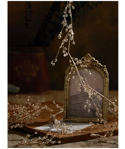 Golden acrylic bead vine garland draped over vintage frames for elegant holiday decor