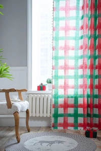 Detail of red and green plaid linen curtain with decorative tassels in a cozy setting
