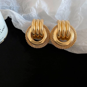 Vue macro de boucles d'oreilles vintage dorées avec texture maille et anneaux torsadés