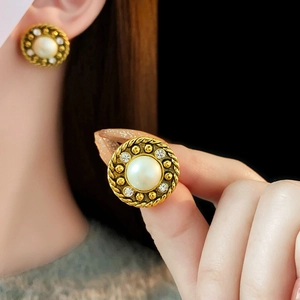 Détail de boucles d'oreilles vintage en perles et cristaux dorés portées par un mannequin