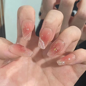 Dettaglio di unghie finte sfumate rosa con nuvole bianche e scaglie di foglia d'oro