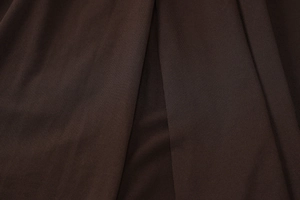 Macro shot of dark brown fabric texture with elegant draping and pleated details