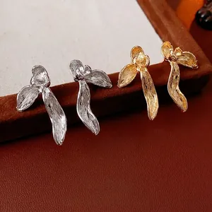 Textured metal orchid petal earrings in gold and silver finishes on velvet