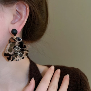 Close-up of leopard print resin flower earrings with vintage metal rose detail on model