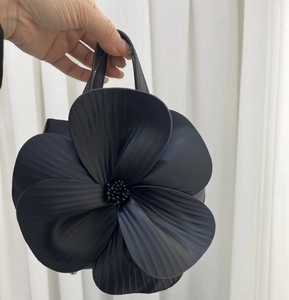 Macro detail of black petal-shaped handbag with intricate beadwork and pleated texture