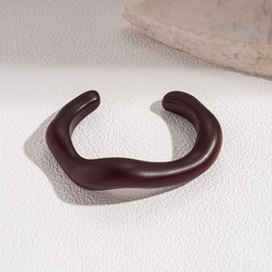 Close-up of brown wavy irregular acrylic open bangle with minimalist matte resin finish