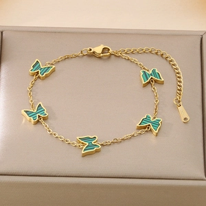 Macro view of gold butterfly bracelet with green malachite-style pendants in a jewelry box