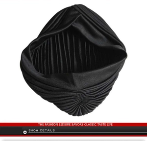 Detail view of the black layered pleated turban hat showing rich fabric texture