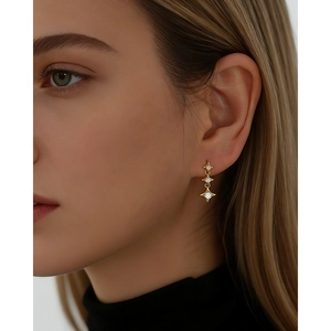 Boucles d'oreilles pendantes triple étoile en argent S925 doré avec zircons sur un mannequin