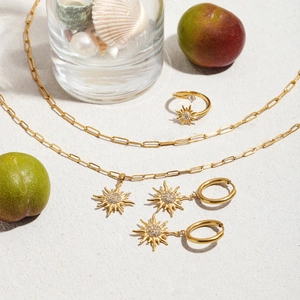 Golden sun motif jewelry set with necklace, earrings and ring on beach-themed decor