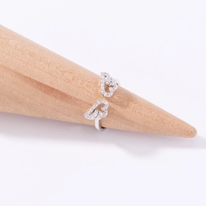 Detailed view of a silver angel wing ring with pavé zircons on a wooden cone stand