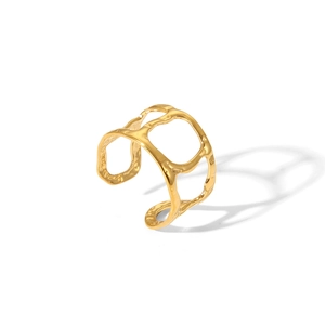 Détail d'une bague large dorée aux motifs évidés irréguliers sur fond blanc