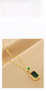 Detailed view of a gold pendant necklace with a rectangular green gemstone and diamonds