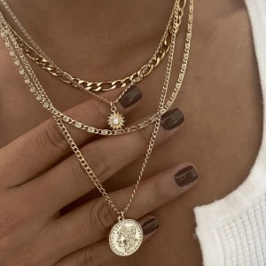 Detailed view of layered gold necklaces with sunburst pendant and vintage coin charm