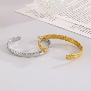 Detail of twisted rope design on gold and silver stainless steel C-shaped bangles