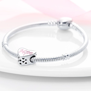 Vista macro del charm a cuore in argento con incisione Hope rosa e motivo traforato