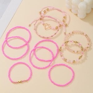 Detailed flat lay of a 9-piece pink and gold beaded bracelet set with heart charms