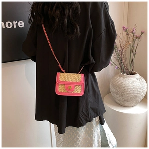 Detail of pink PU leather trim on beige straw bag with gold flower buckle and chain