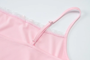Close-up of pink ribbed camisole with white lace trim and adjustable silver buckle straps