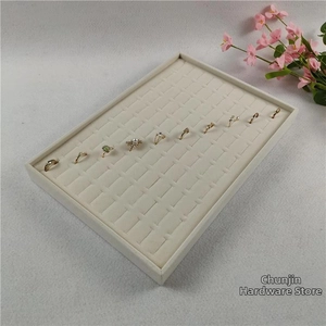 Macro shot of large jewelry tray with soft beige velvet slots displaying various rings