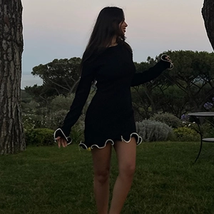 Dettaglio dell'abito corto in maglia nera con eleganti bordi ondulati bianchi a contrasto